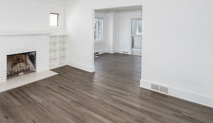 Empty living room with grey wood look flooring and white fireplace