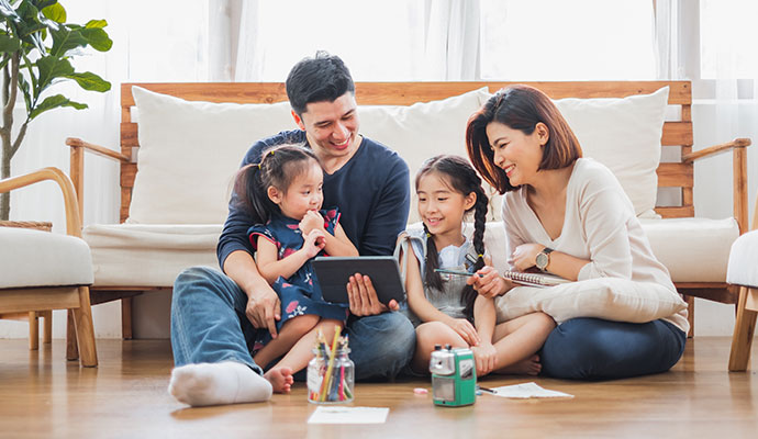 Happy family sitting on clean wood floor in living room
